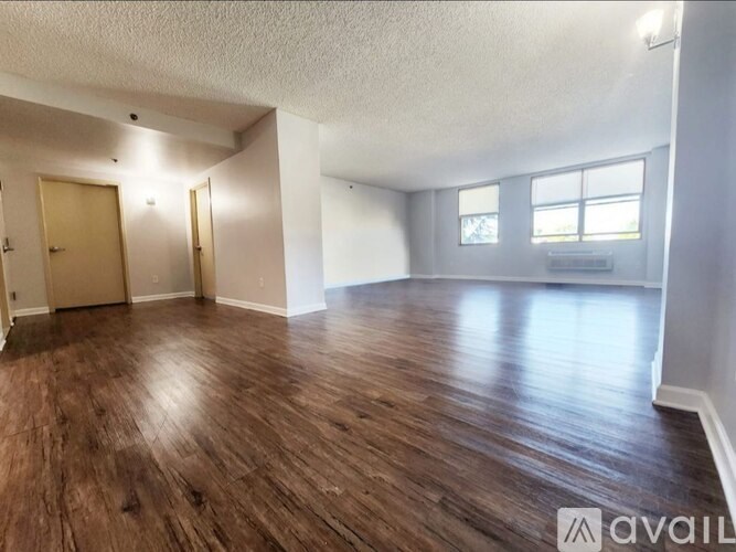 A spacious room with wooden flooring and two doors.