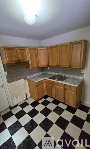 A kitchen with wooden cabinets and a checkered floor.