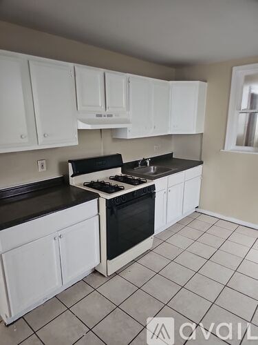 A kitchen with white cabinets and black countertops.