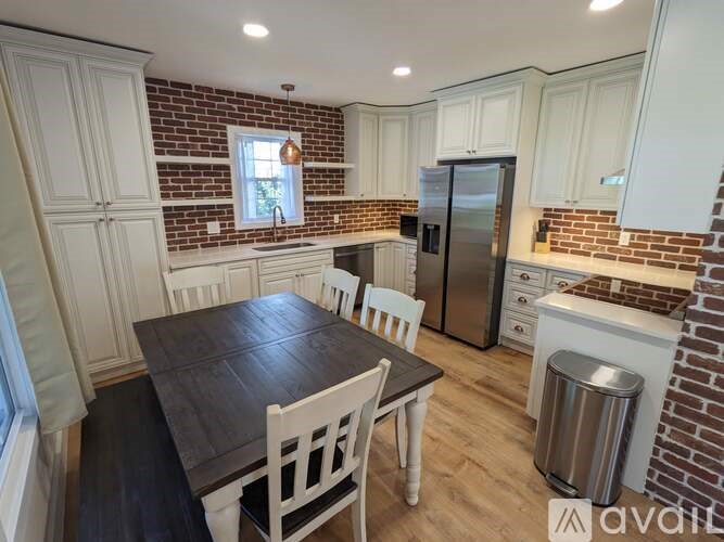 A kitchen with a table and chairs in the foreground and a brick wall above the counter.