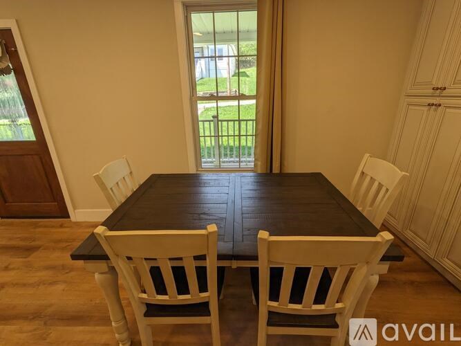 A dining room with a black table and white chairs.