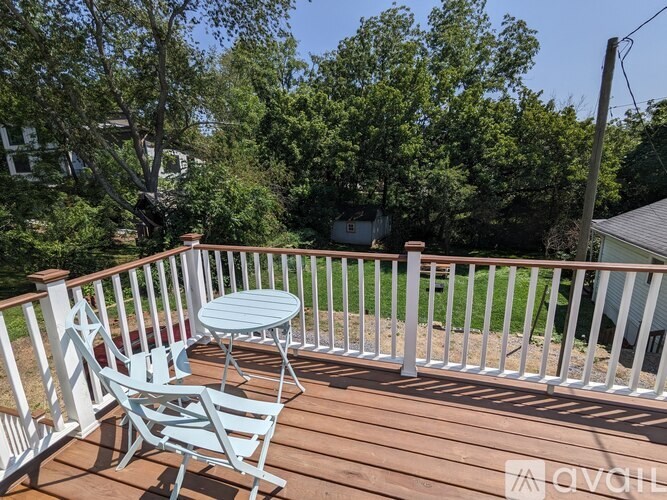 A wooden deck with a white railing, a small table and two chairs.