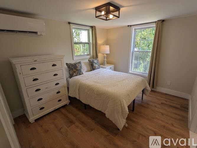 A bedroom with a bed, dresser, and window.