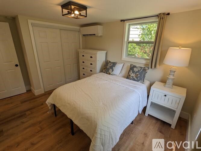 A bedroom with a bed, nightstand, and window.