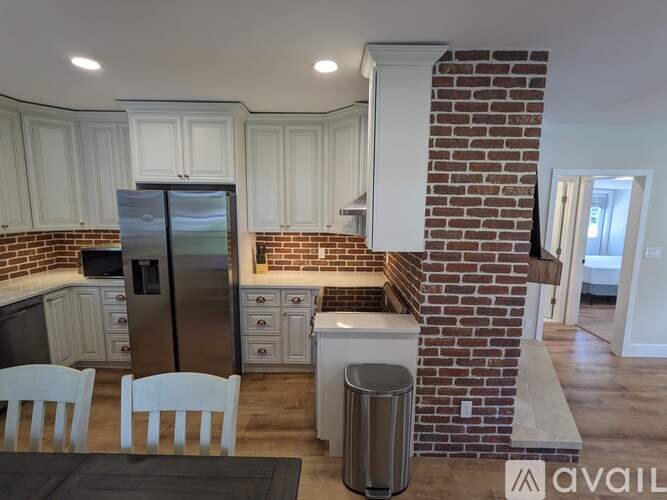 A kitchen with a brick wall and white cabinets.