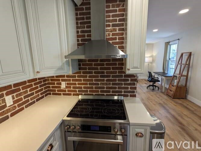 A kitchen with a stove top oven and a brick wall.