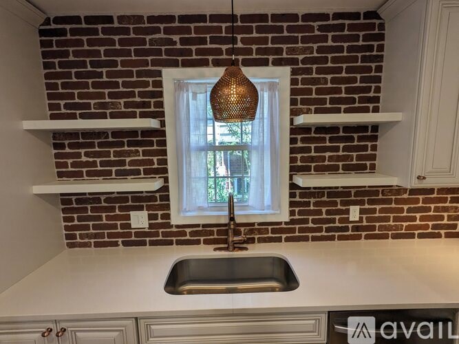 A kitchen with a brick wall and a window above the sink.