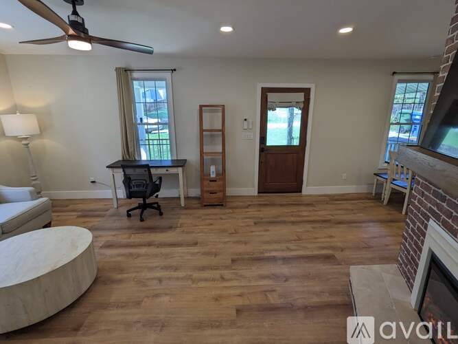 A room with a wooden floor and a fireplace on the right side.