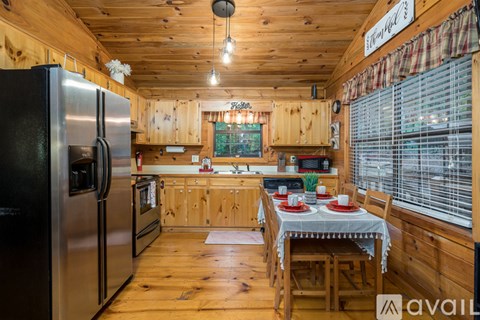 A kitchen with wooden walls and a black refrigerator.