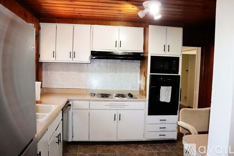 A kitchen with white cabinets and appliances, a sink, and a refrigerator.