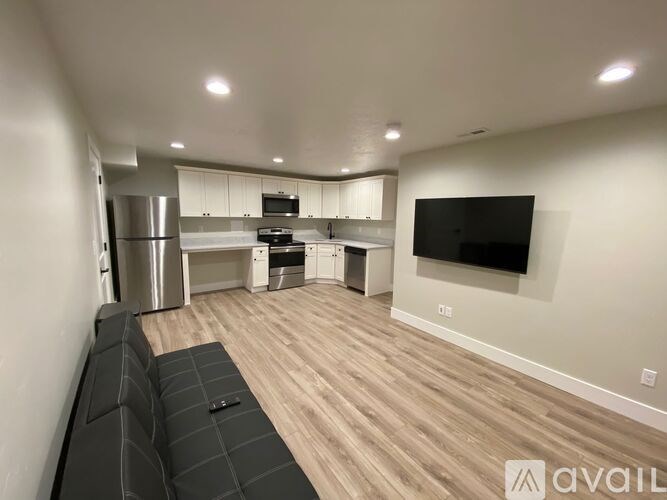 A modern living room with a grey sofa and a flat screen TV mounted on the wall.