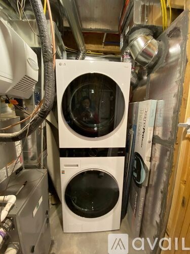 A white washing machine with a black door is in a cluttered room.