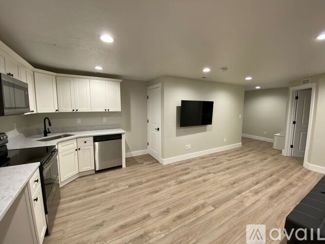 A spacious kitchen and living room with wood flooring and white cabinetry.