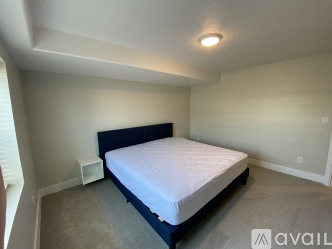 A bedroom with a bed, nightstand, and a window.