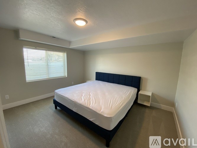 A bedroom with a bed, nightstand, and window.