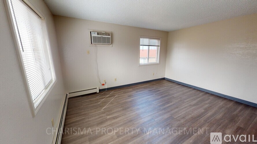 A room with wooden flooring and a window with blinds.