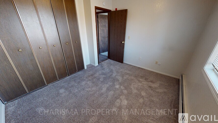 A room with a carpeted floor and a wooden door.