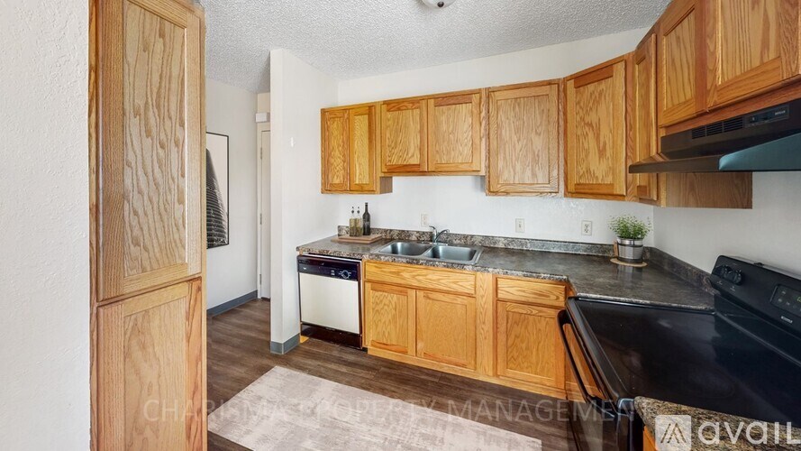 A kitchen with wooden cabinets and a black dishwasher.