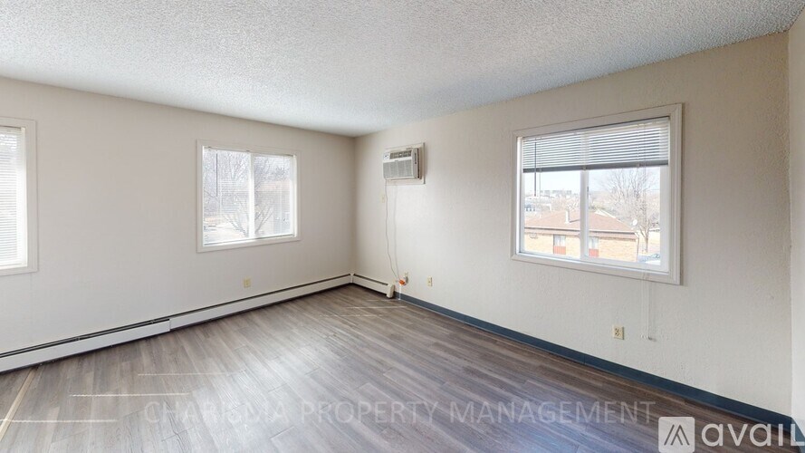 A room with a window and a wooden floor is available for rent.