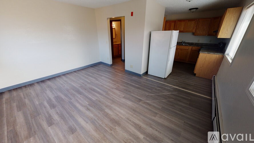 A room with wooden flooring and a white refrigerator.