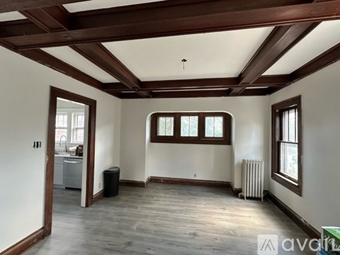 A spacious room with wooden beams and a window with a view of trees.