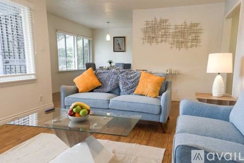 A living room with a blue couch and a glass coffee table.