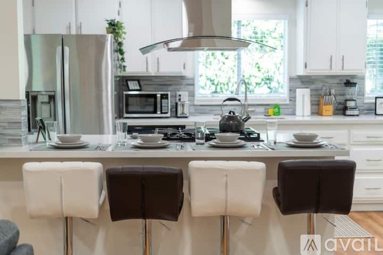 A modern kitchen with white cabinets and a central island with a sink and a microwave.