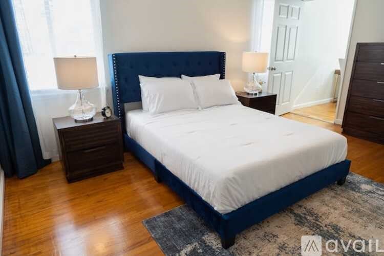 A bedroom with a large bed, two nightstands, and a rug.