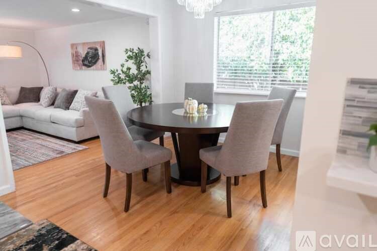 A modern dining room with a round table and grey chairs.