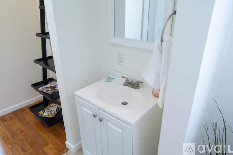A white bathroom with a sink and a towel hanging on the wall.