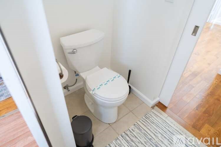 A white toilet with a blue design on the lid is in a small bathroom.