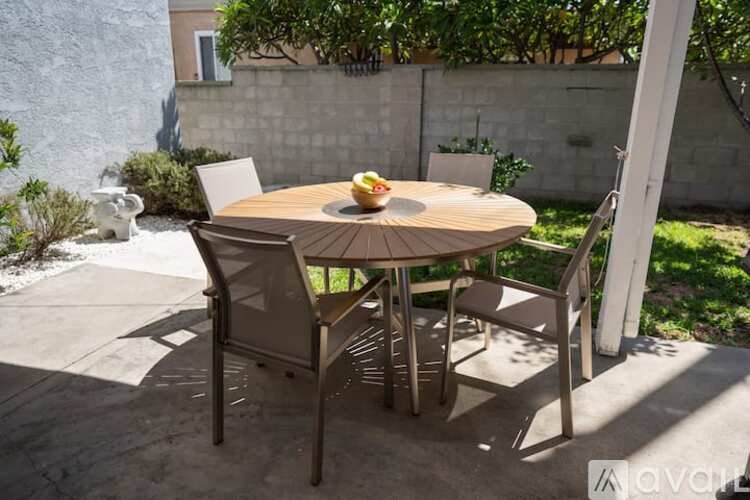 A table with chairs and a bowl of fruit on it is set up outside.