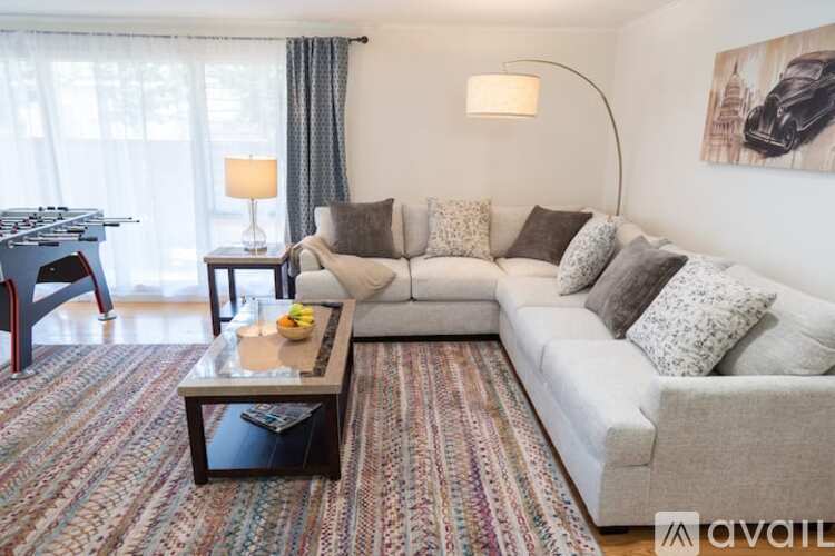 A living room with a grey couch, a coffee table, and a painting on the wall.