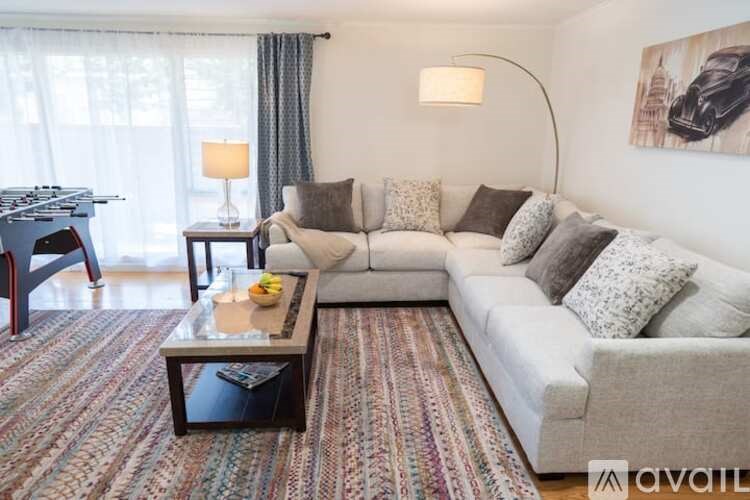 A living room with a grey couch, a coffee table, and a painting on the wall.