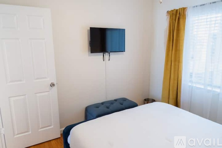 A bedroom with a bed, a bench, and a television.