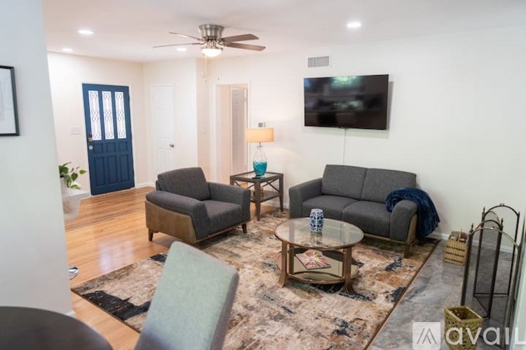 A living room with a grey couch, a coffee table, and a flat screen TV mounted on the wall.