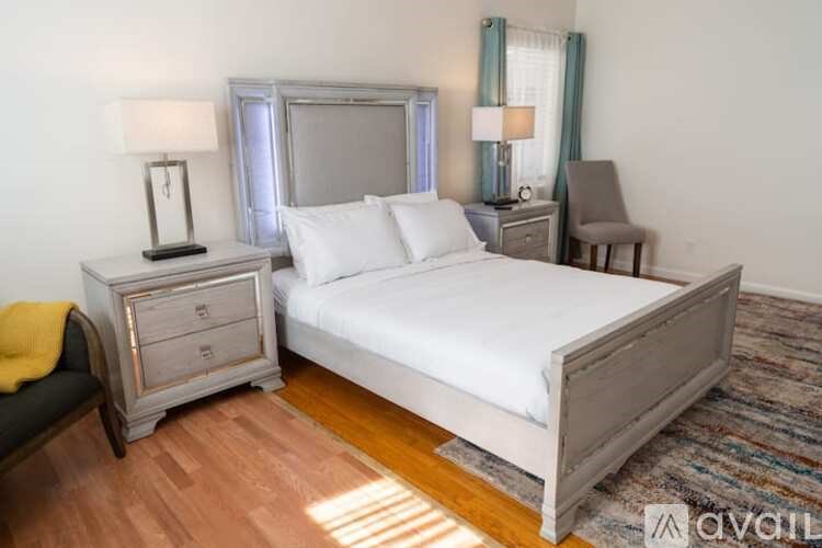 A bedroom with a bed, nightstand, and chair.