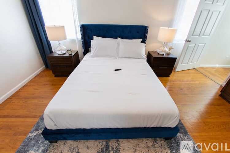 A bed with a white sheet and a blue headboard is in the image.