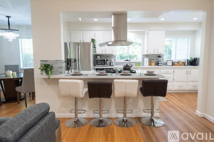 A modern kitchen with white cabinets and a central island with bar stools.