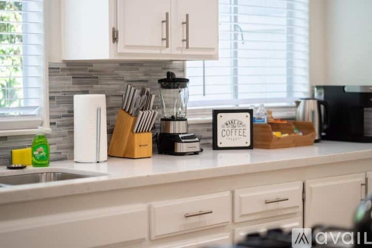 A kitchen counter with a coffee maker and a container of utensils.