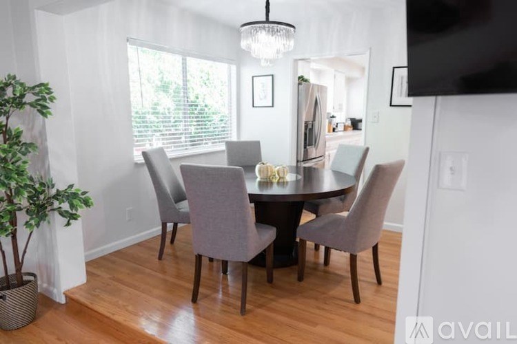 A dining room with a table surrounded by grey chairs.