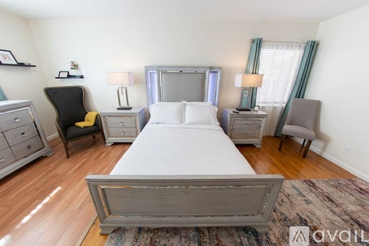 A bedroom with a large bed, a chair, and a dresser.