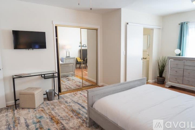 A bedroom with a large bed, a television, and a mirrored closet door.