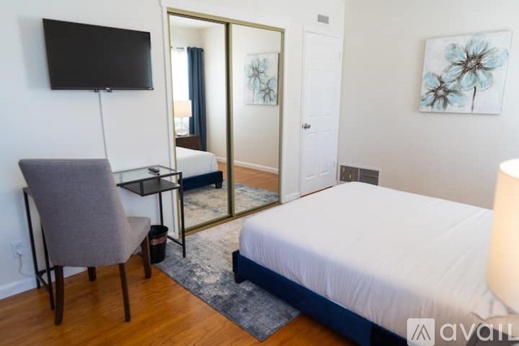 A bedroom with a bed, chair, and a mirror.