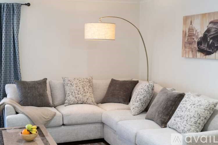 A living room with a grey couch and a bowl of fruit on the table.