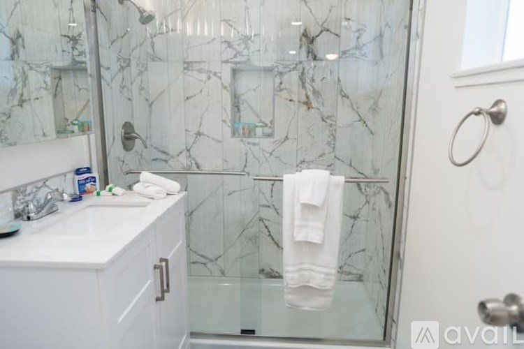 A white towel hangs on a glass shower door.