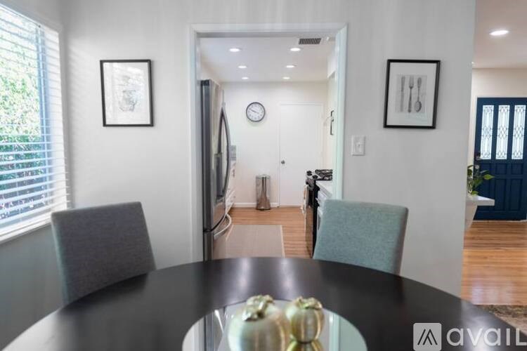A modern dining room with a black table and two grey chairs.