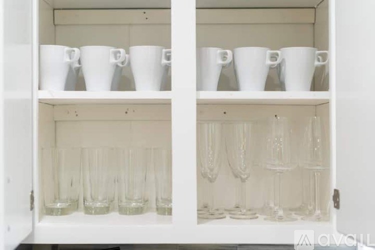 A white cabinet with glasses and cups on the shelves.