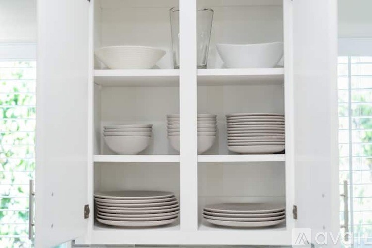 A white cabinet with plates and bowls on the shelves.