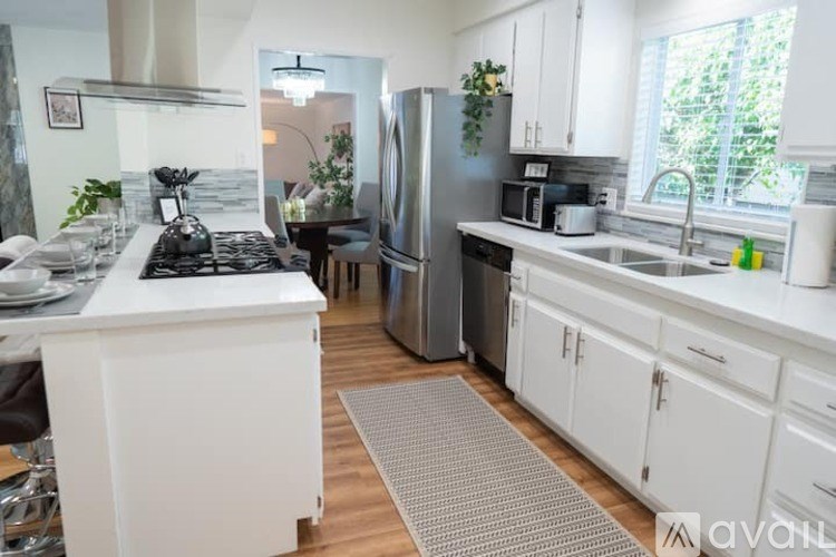 A kitchen with white cabinets and a grey refrigerator.
